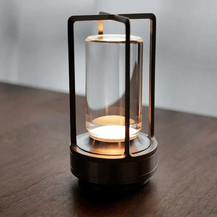 Modern lantern-style lamp with glass cover on a wooden surface