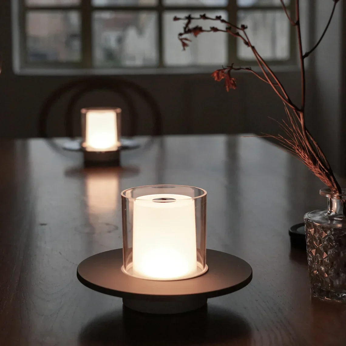Candle in a glass holder on a wooden surface with a blurred background