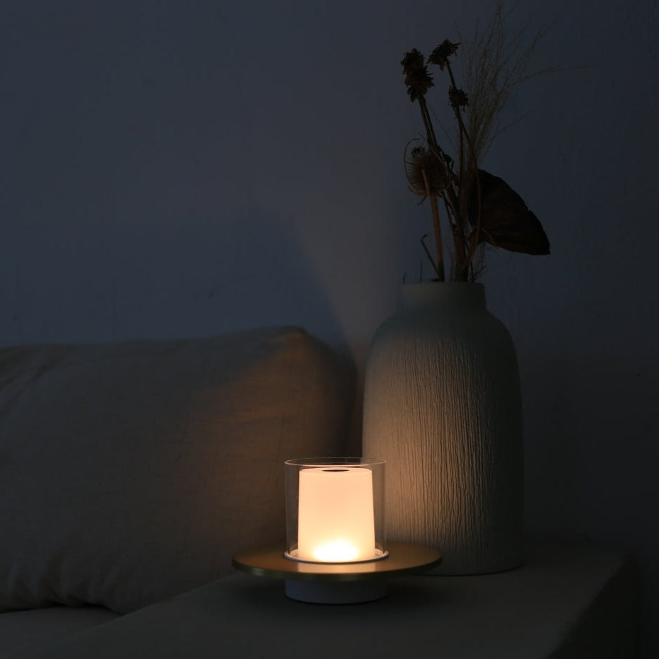 Candle and vase with dried plants on a dark surface