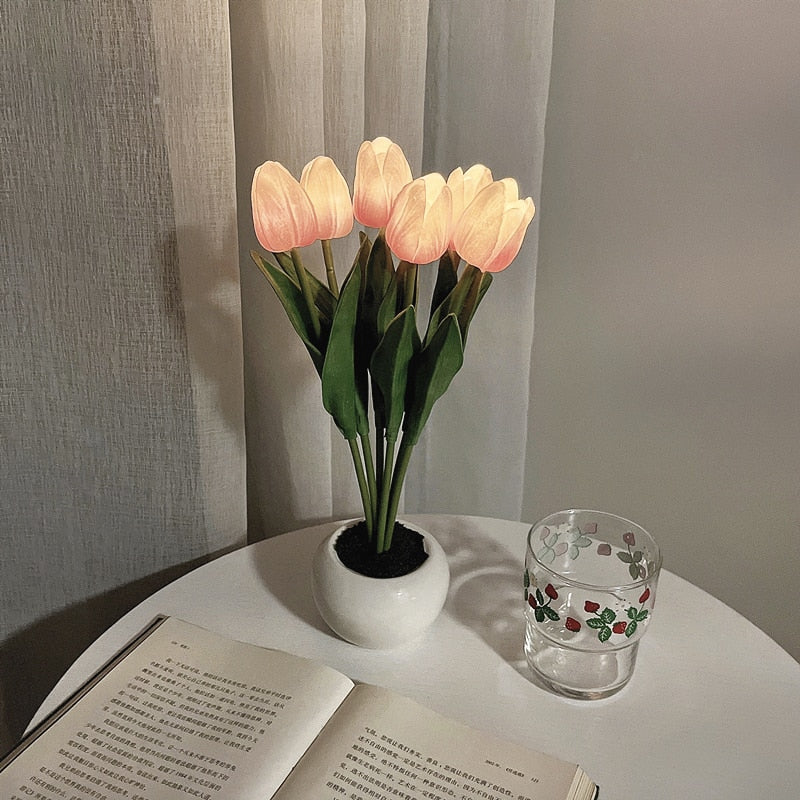 Potted tulips on a table with a book and glass