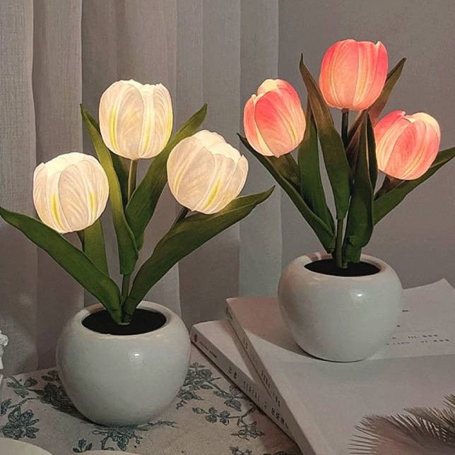 Two potted tulip-shaped lamps on a surface with a neutral background
