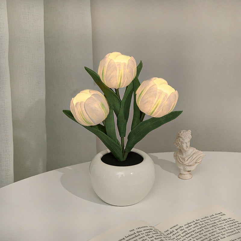 Decorative potted plant with illuminated bulbs on a table next to a classical statue.