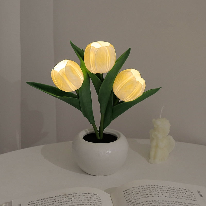 Decorative lamp shaped like a potted plant with glowing yellow lights on a table.