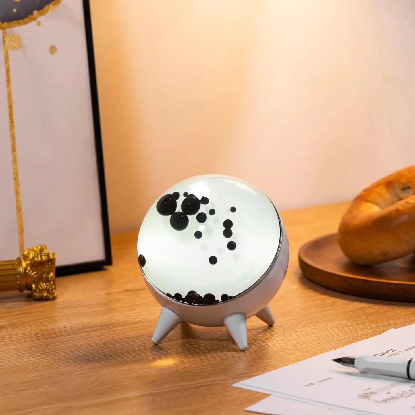 Round night light with black dots on a wooden surface