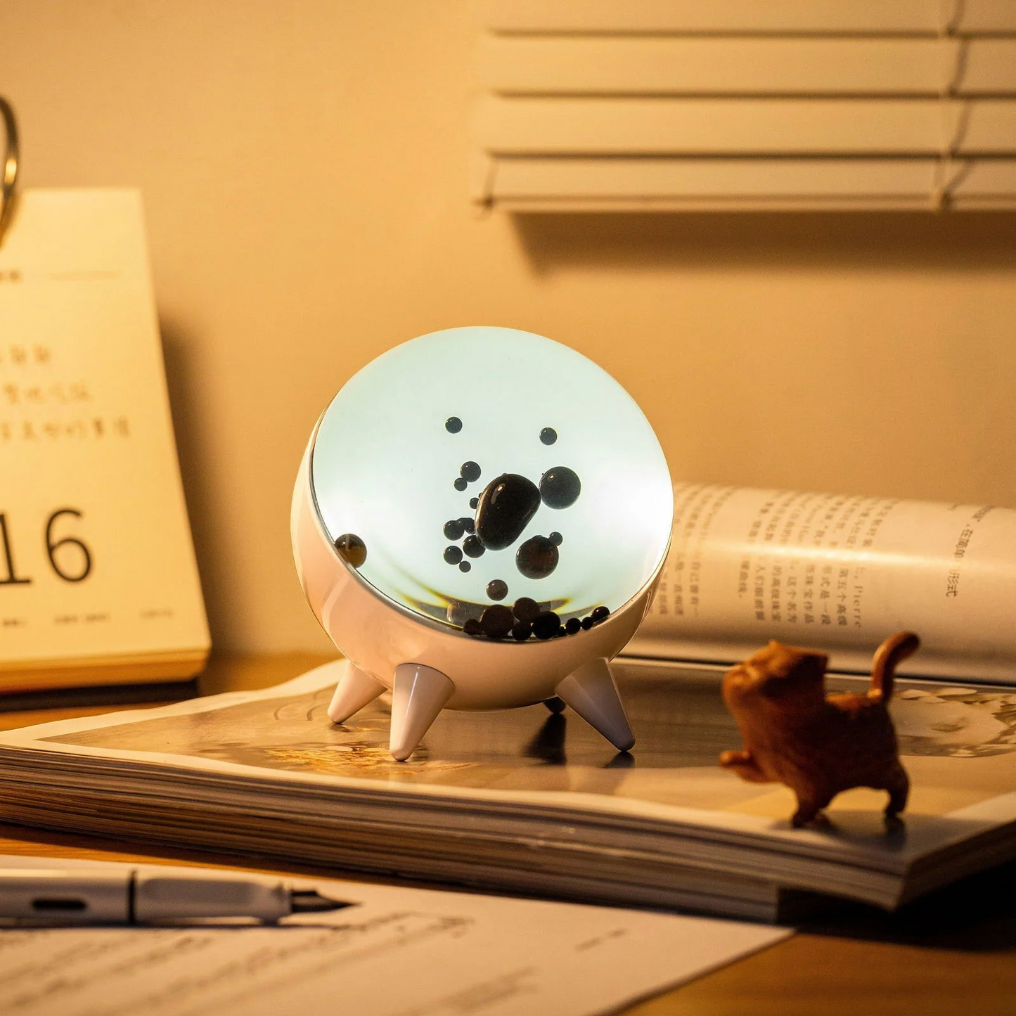 Decorative lamp with a circular design on top of a notebook with a small figurine beside it.