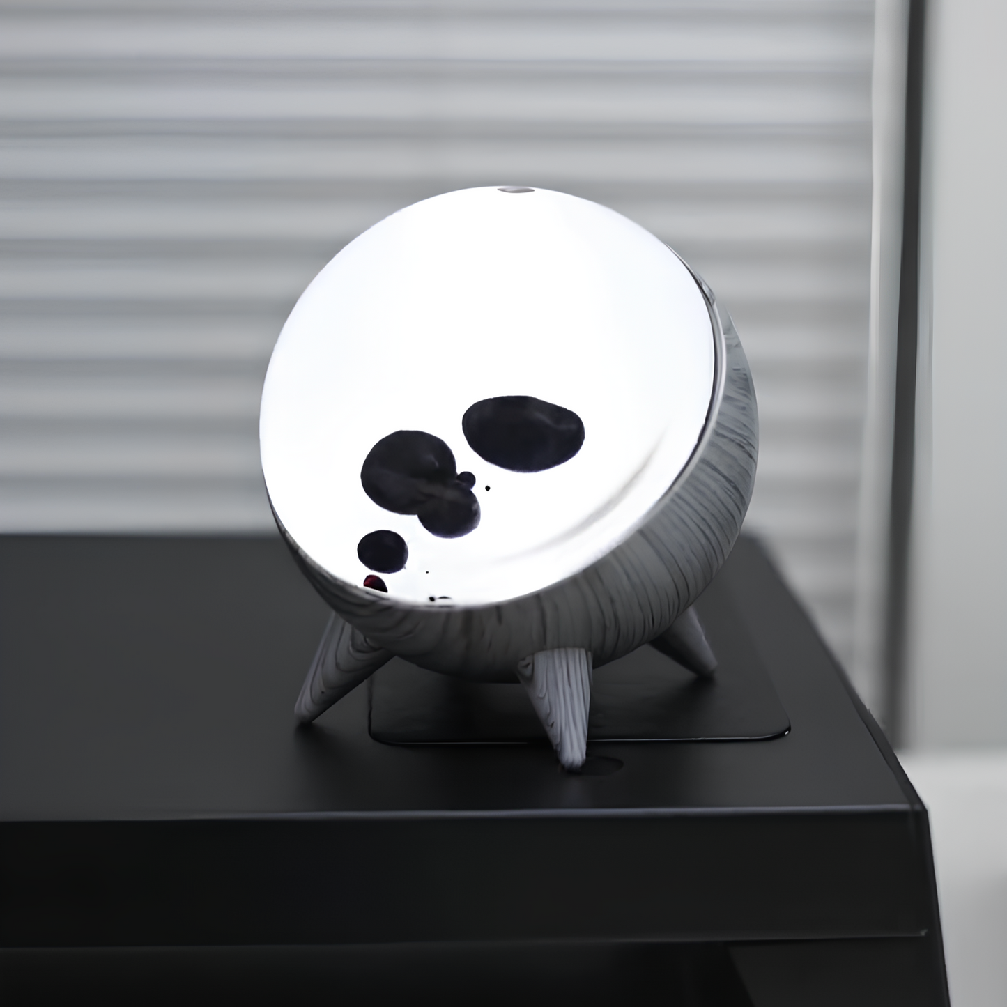 Round white object with black spots on a stand against a neutral background