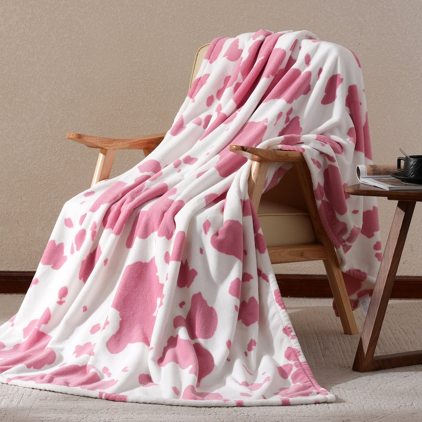 Pink and white patterned blanket draped over a wooden chair against a beige wall.