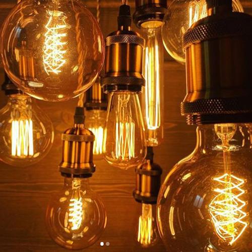 Vintage-style light bulbs with glowing filaments on a reflective surface.