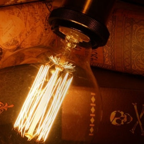Vintage-style light bulb with intricate filaments on a textured surface