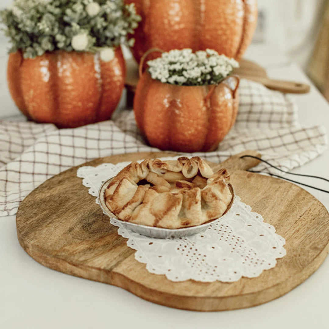 Josh & Tate - Pumpkin Wooden Cutting Board - Apple pie on a wooden cutting board with pumpkins and flowers in the background