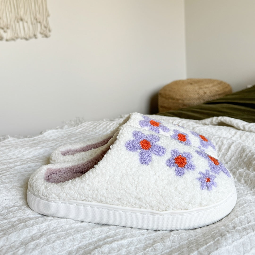 White slippers with floral embroidery on a textured surface