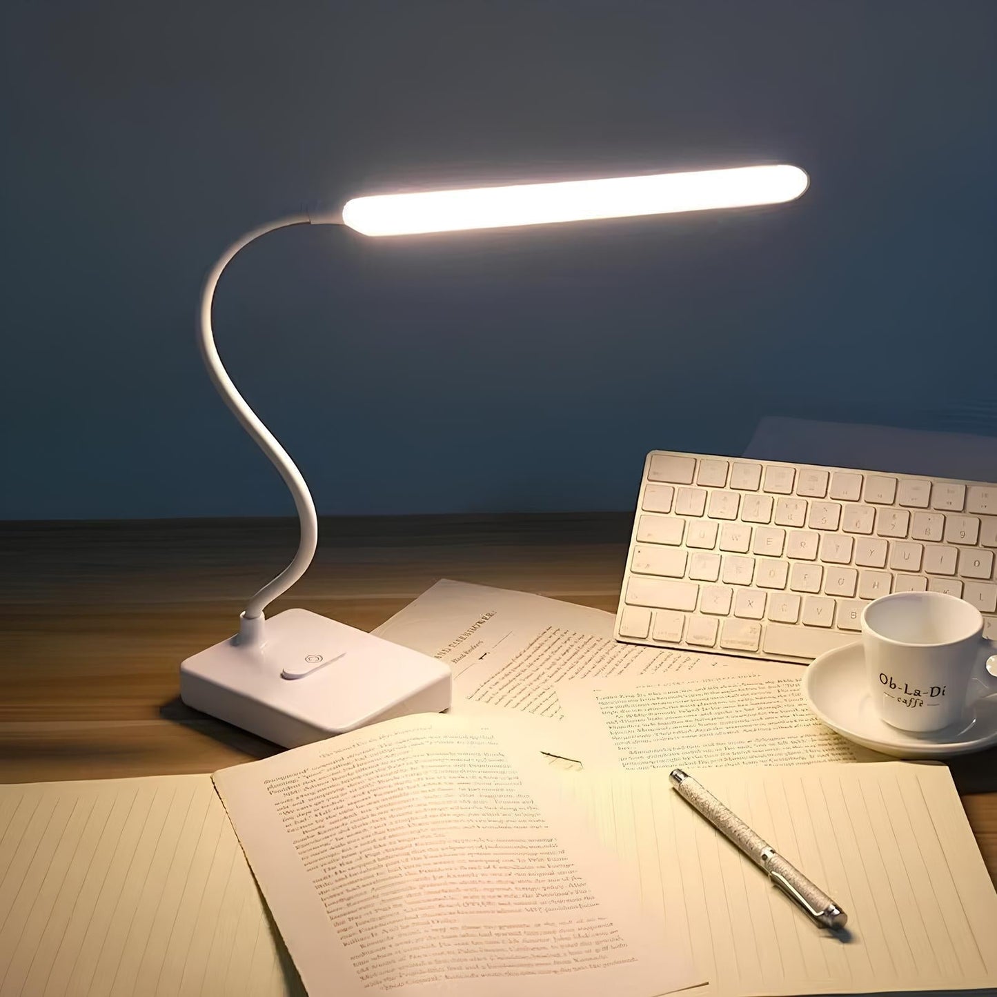 Desk setup with a white LED desk lamp, keyboard, and papers on a wooden surface.