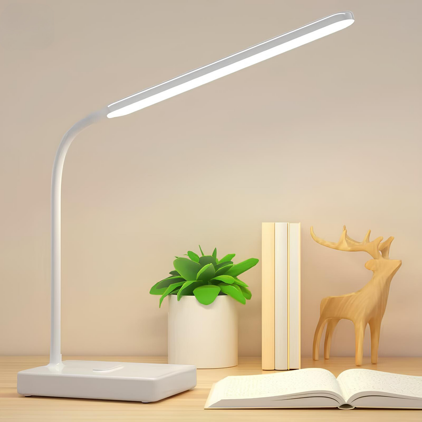 White LED desk lamp on a wooden surface with a plant, book, and wooden deer ornament.