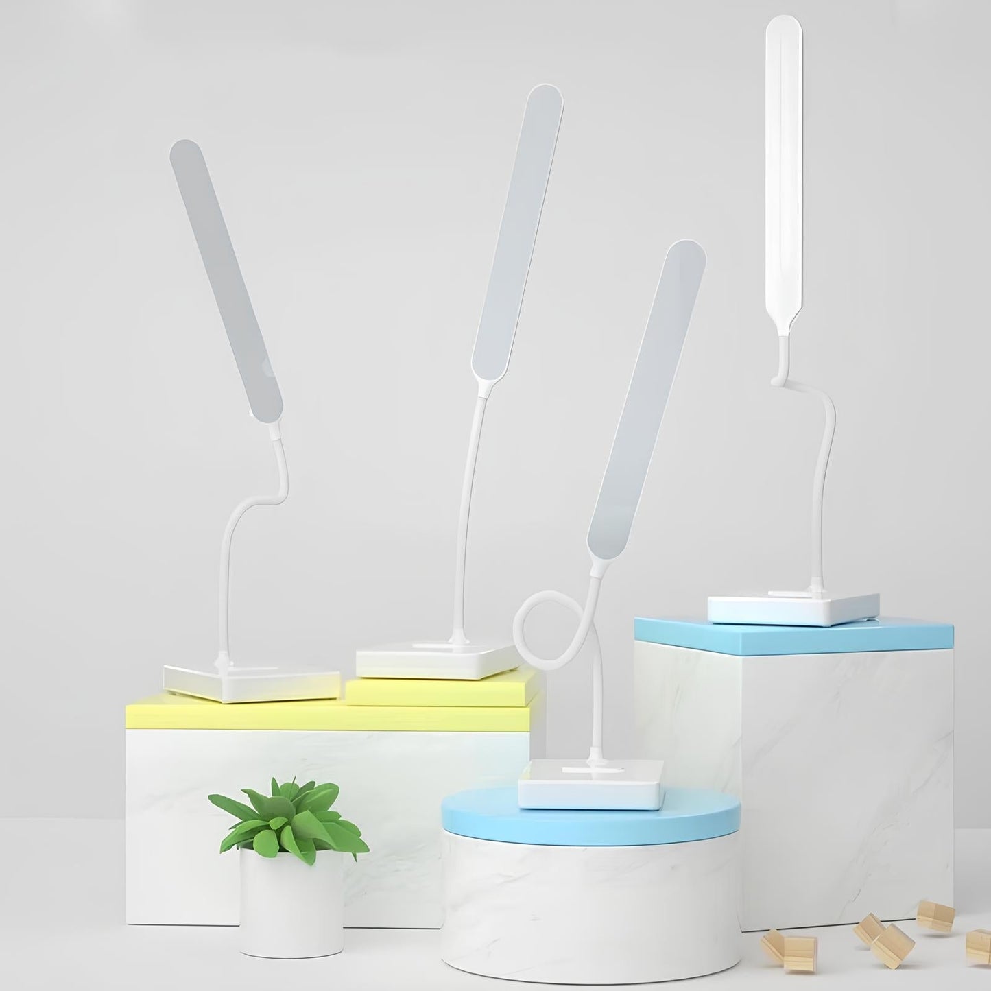 Set of desk lamps on cylindrical stands with a small plant and wooden blocks on a light gray background