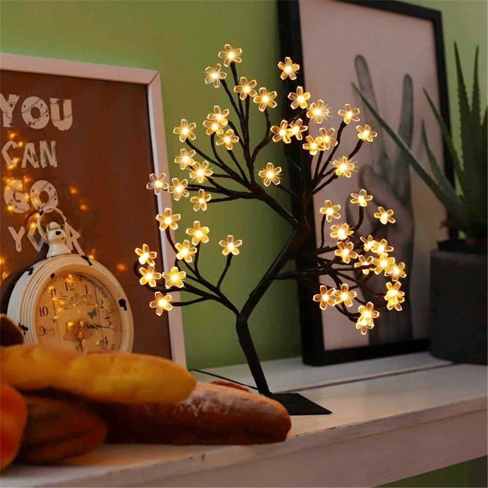 Decorative LED tree on a shelf with a clock and plant in the background