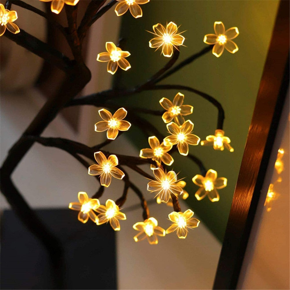 Flower-shaped string lights on a branch with a blurred background
