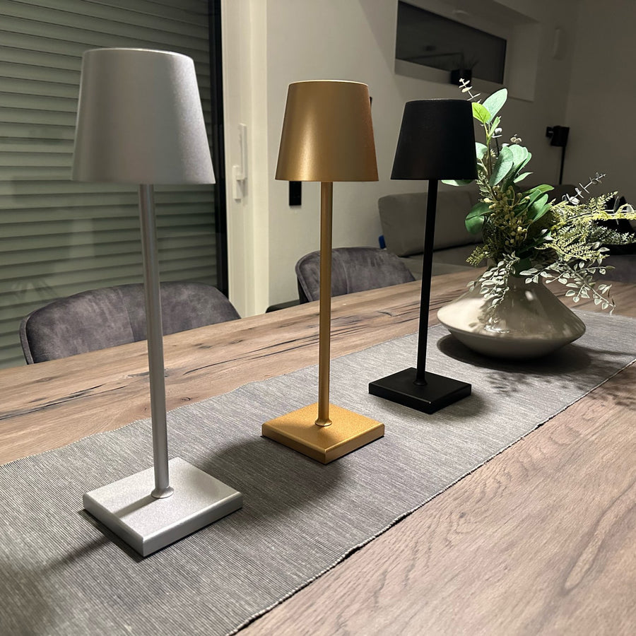Three table lamps on a wooden table with a plant in the background