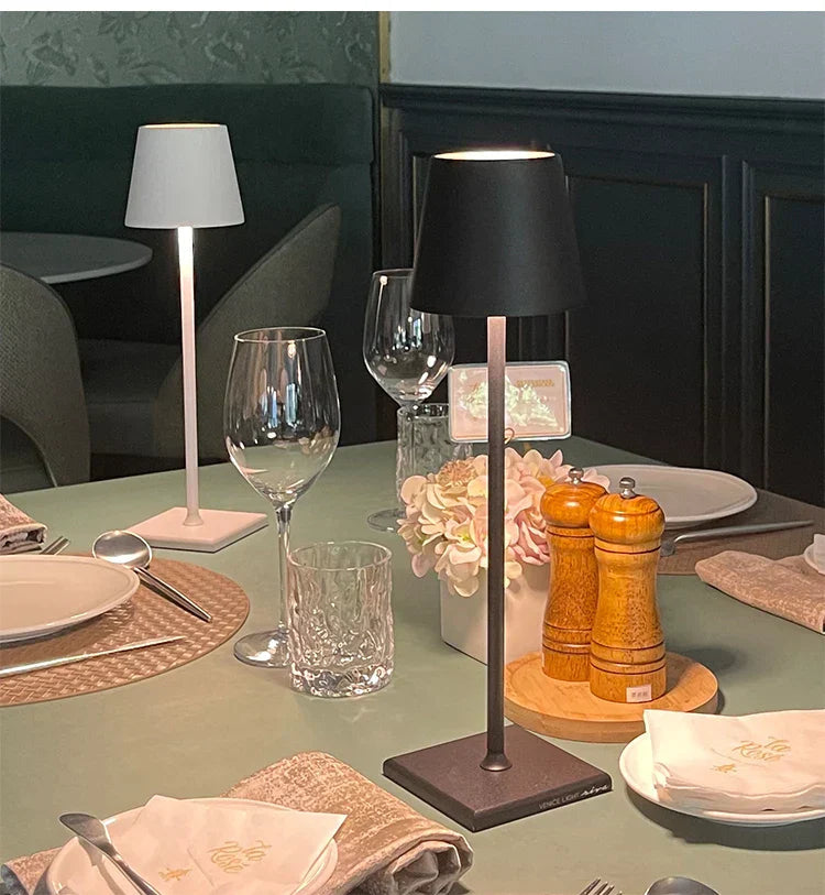 Table setting with a black table lamp, glasses, and cutlery in a restaurant.