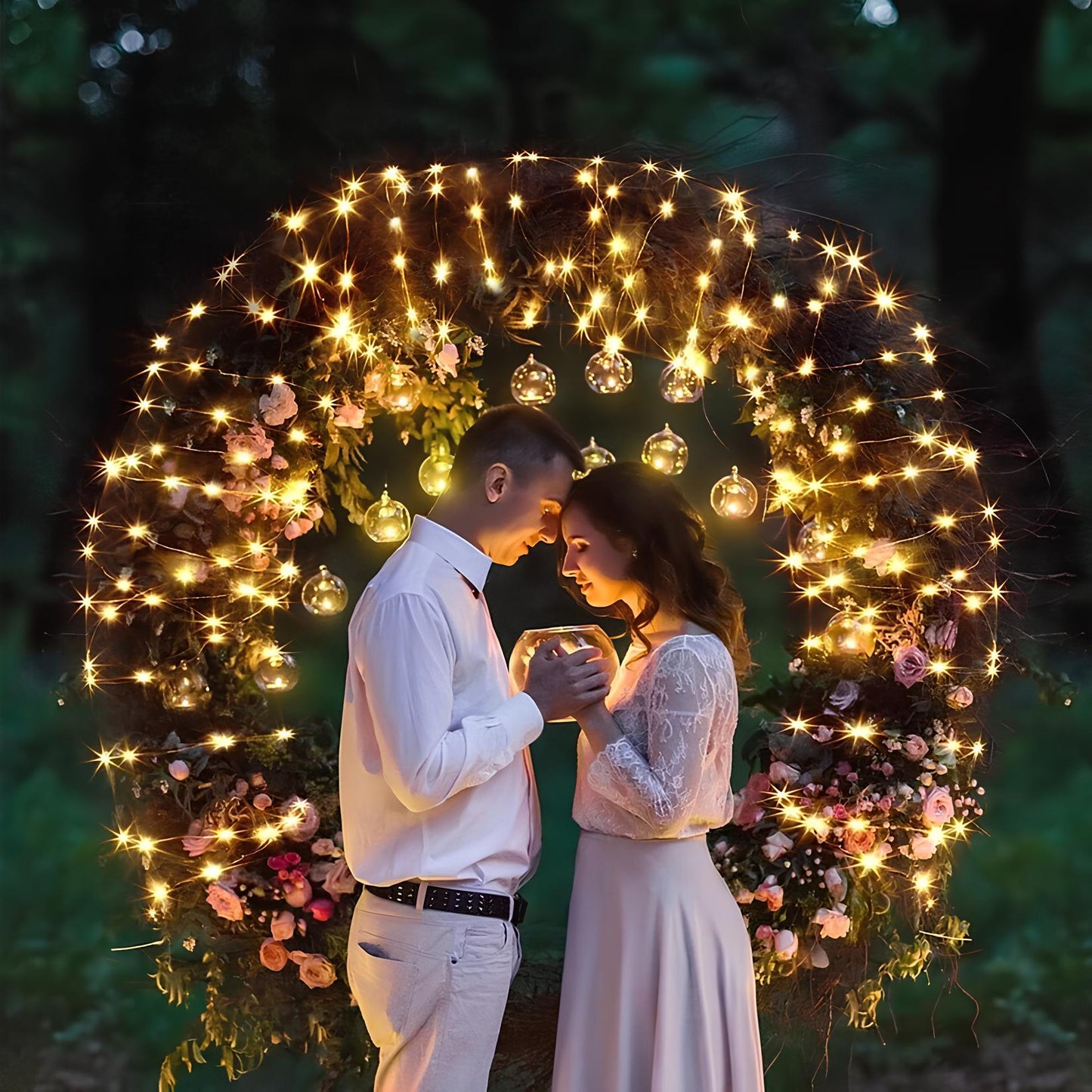 Couple standing under a decorative arch with lights and flowers, surrounded by a dark green background.