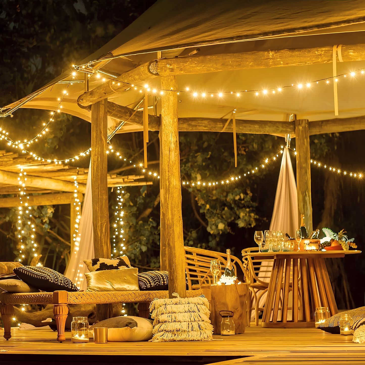 Outdoor evening setting with string lights, furniture, and a table with drinks.