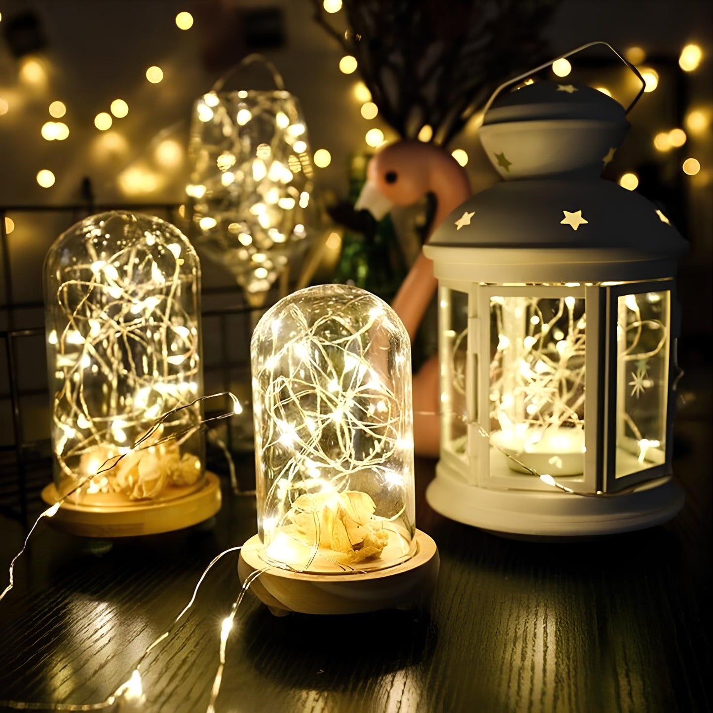 Decorative lanterns with string lights on a wooden surface