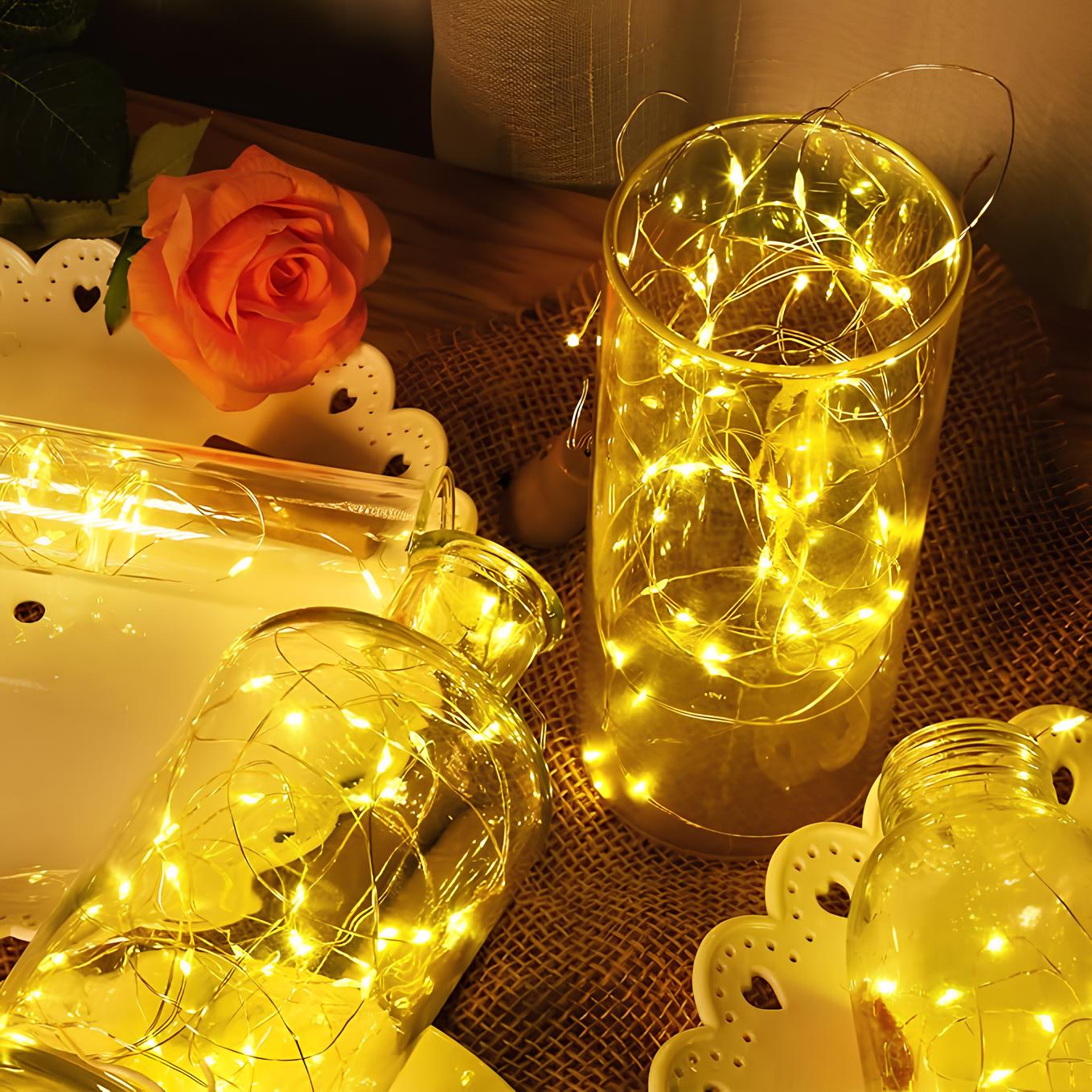 Decorative glass jars with string lights on a textured surface.