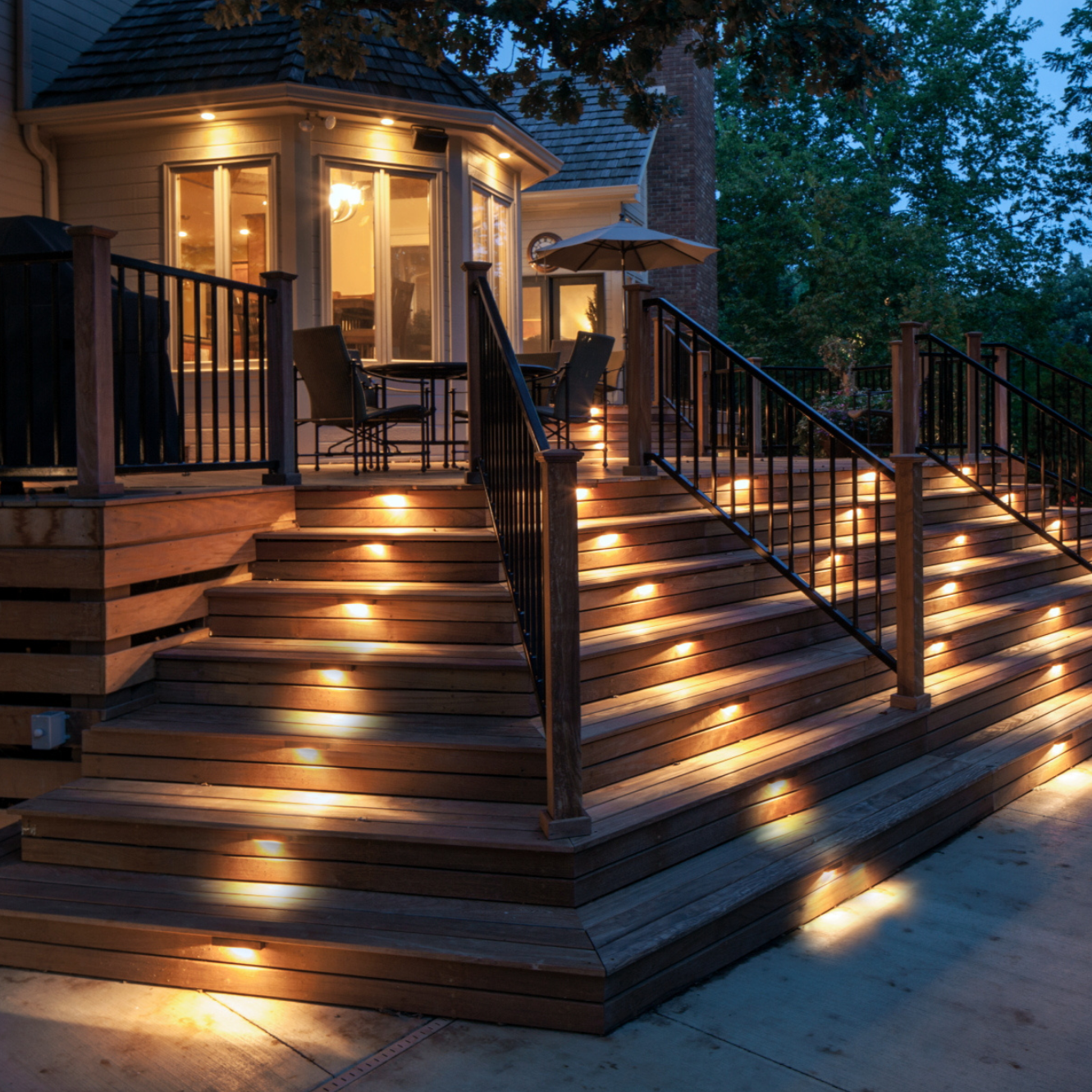 Wooden deck with illuminated steps and railing at night