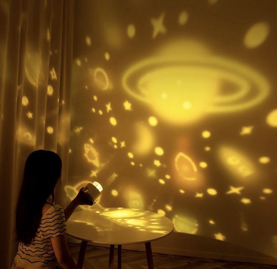 Person sitting at a table with a starry night light projection on the wall.
