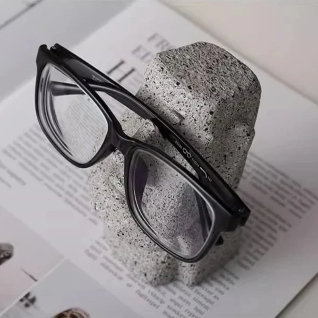 Black eyeglasses on a textured stone block with a magazine background