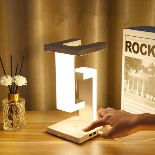 Modern table lamp on a wooden surface with a hand adjusting it, next to a vase and a book.