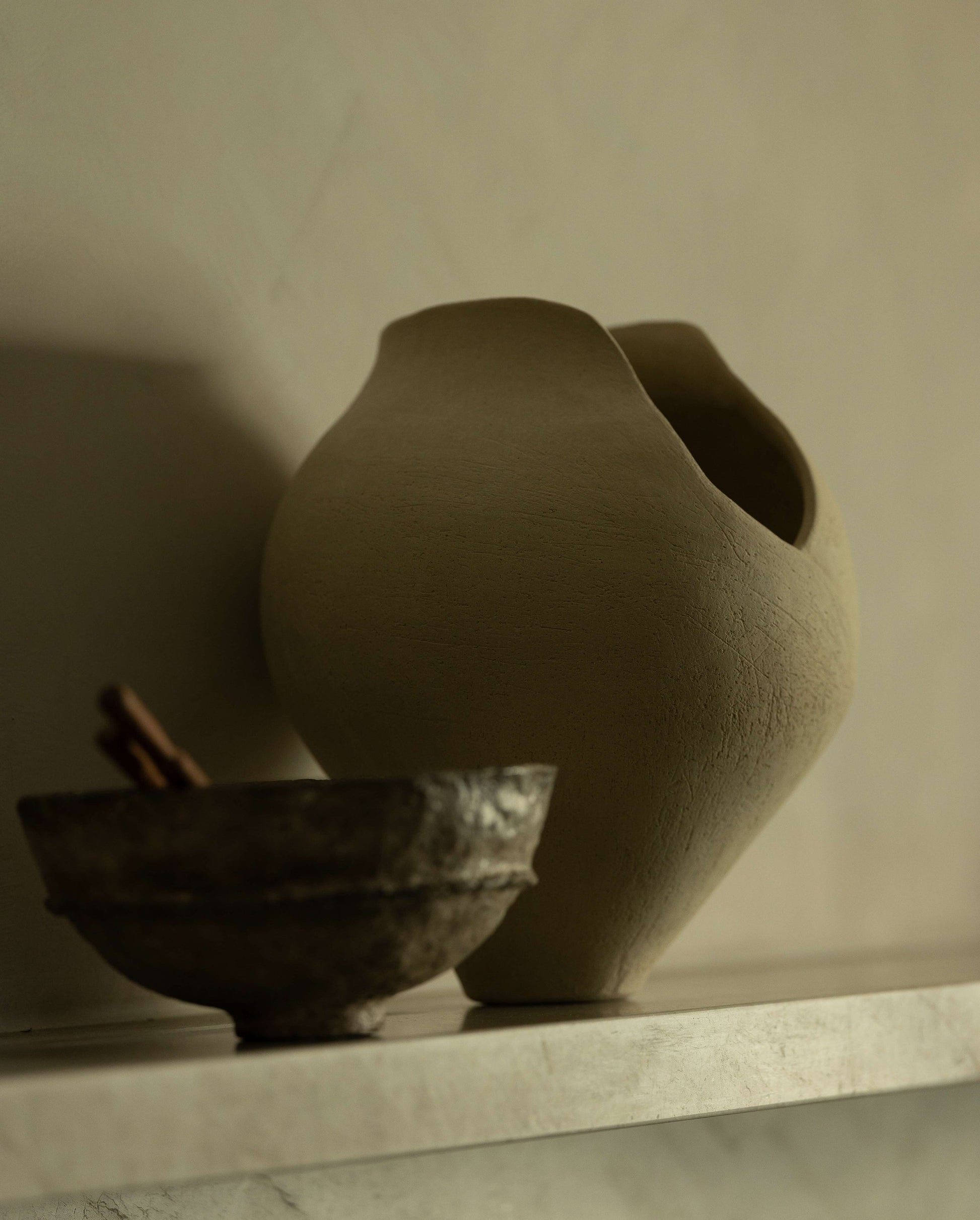 Two ceramic pots on a shelf with a neutral background