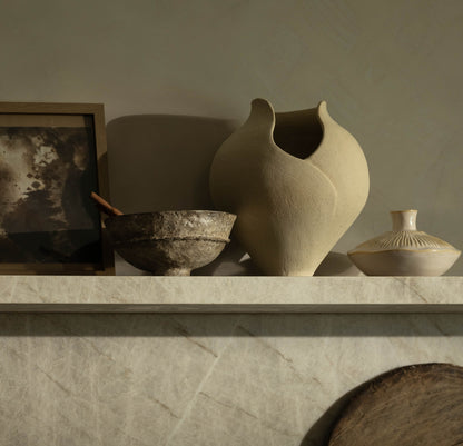 Decorative shelf with ceramic vases and bowls against a neutral wall.