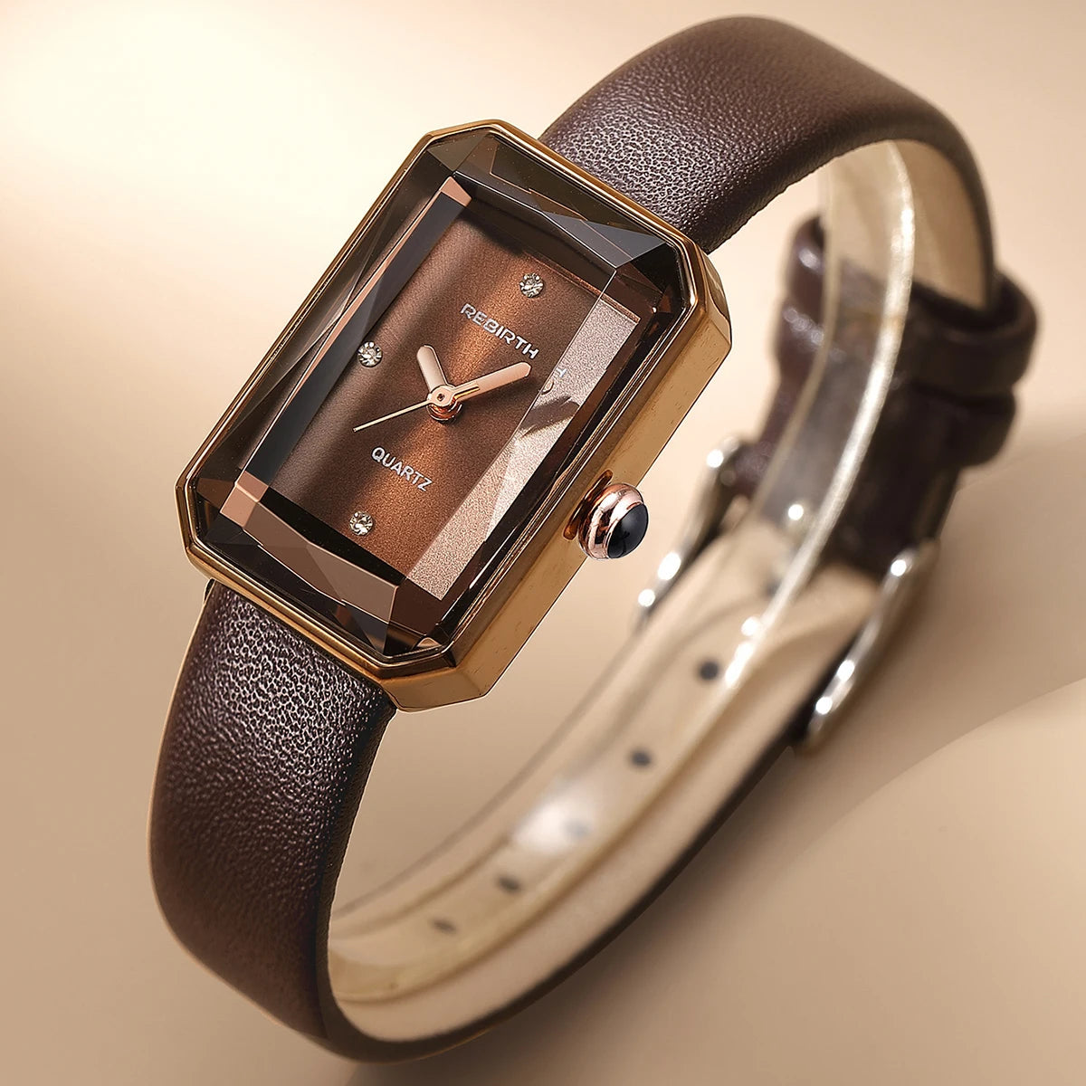 Brown wristwatch with a gold case on a beige background