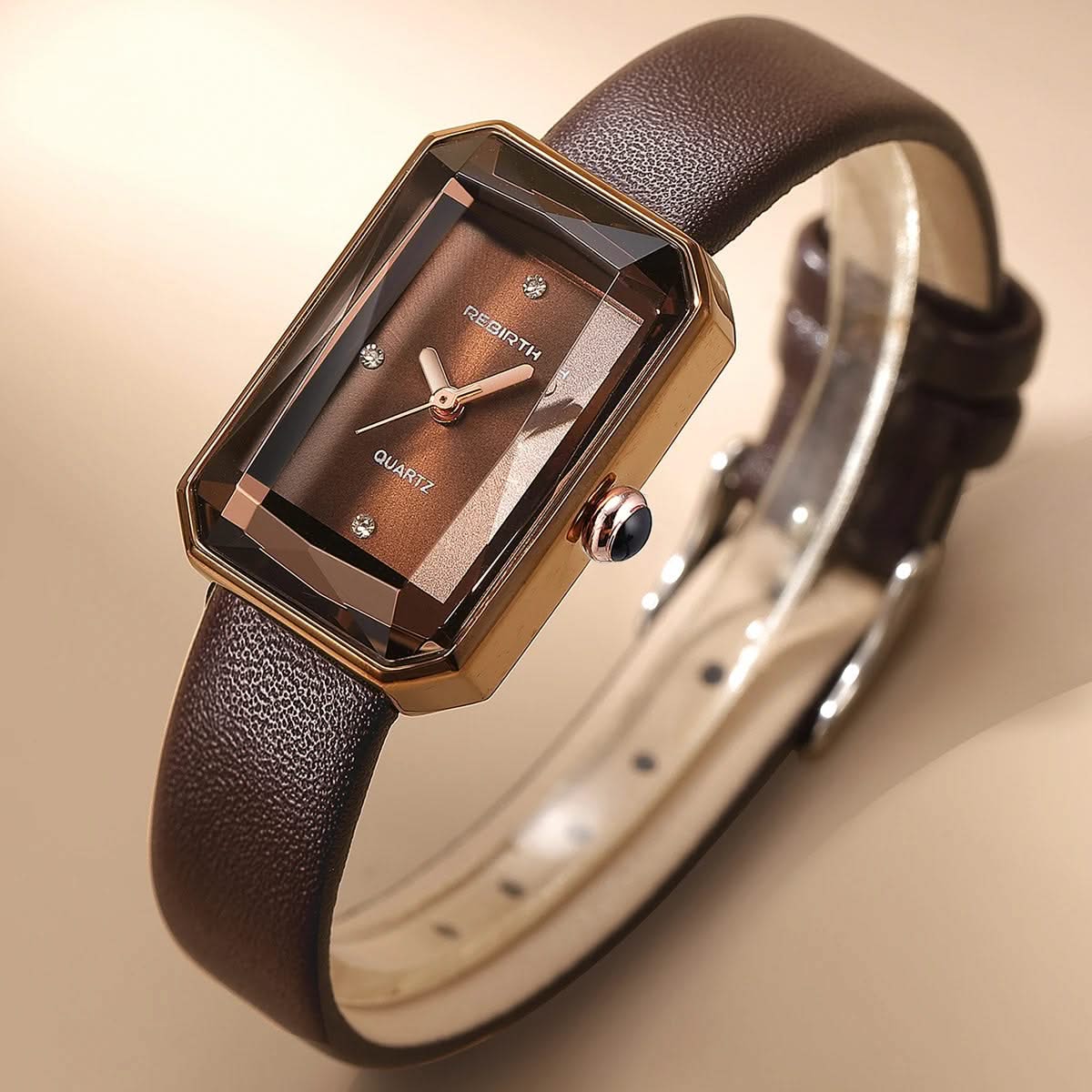 Brown wristwatch with a gold case on a beige background
