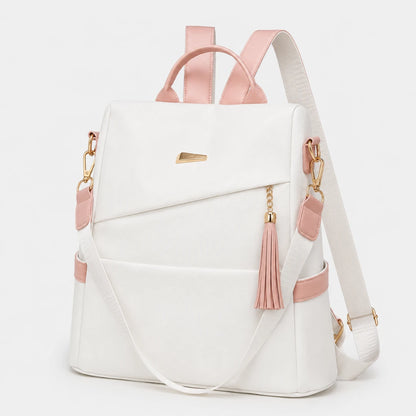 Josh & Tate - AntiTheft™ Oxford Backpack - A white backpack with light pink leather-like accents, gold-tone hardware, and a pink tassel charm, shown on a clean white background.