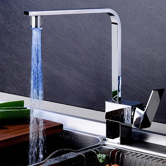 Modern kitchen faucet with water flowing into a sink against a dark gray background
