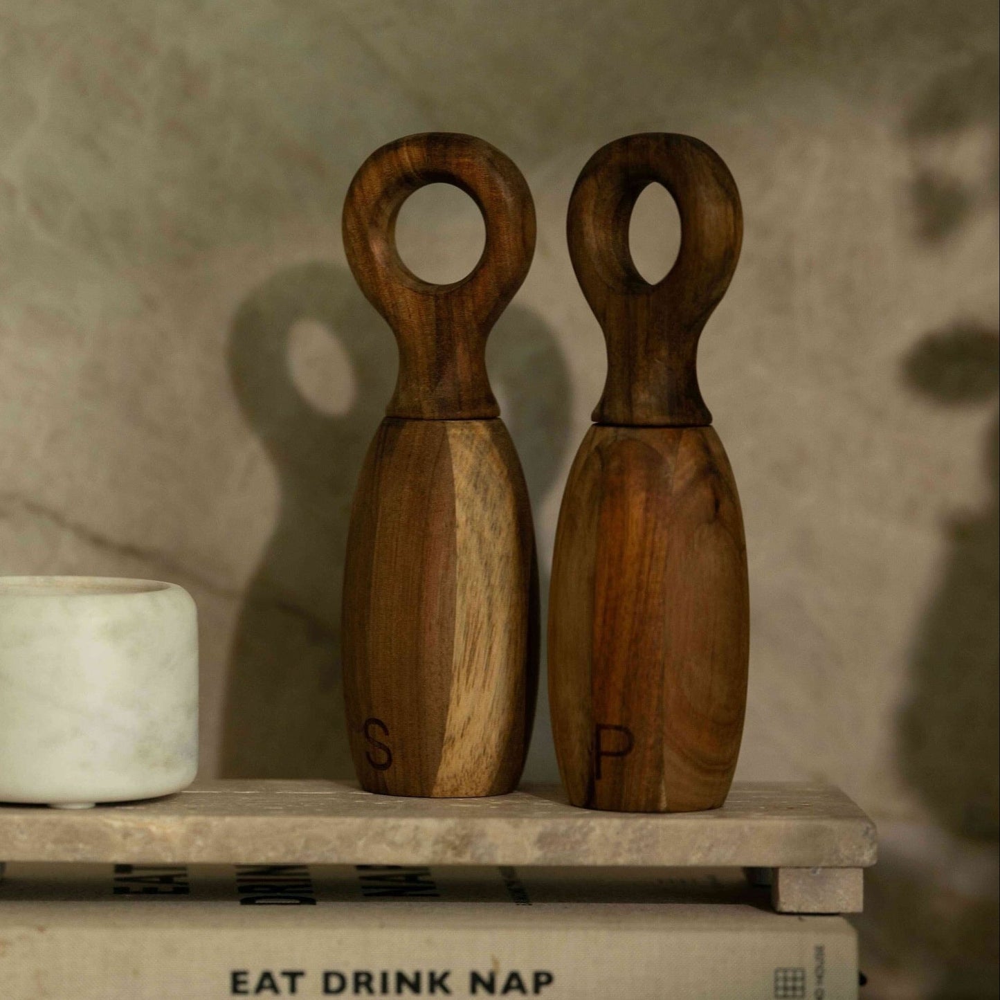 Two wooden salt and pepper shakers on a rustic surface with a neutral background.