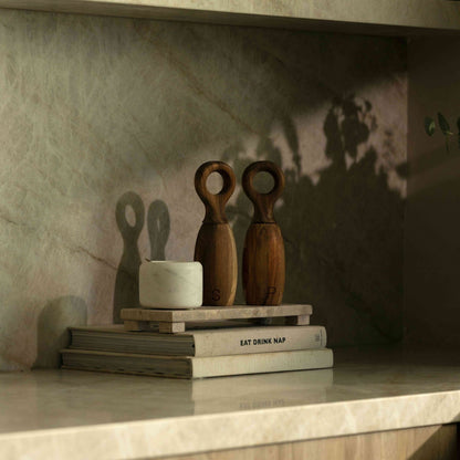 Wooden objects and books on a marble surface with a textured wall background