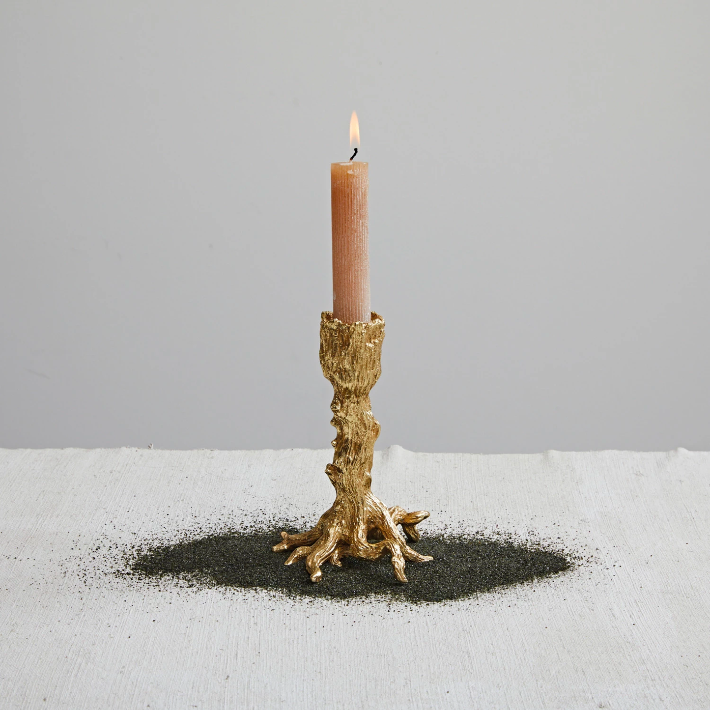 Candle in a decorative gold holder on a light gray background