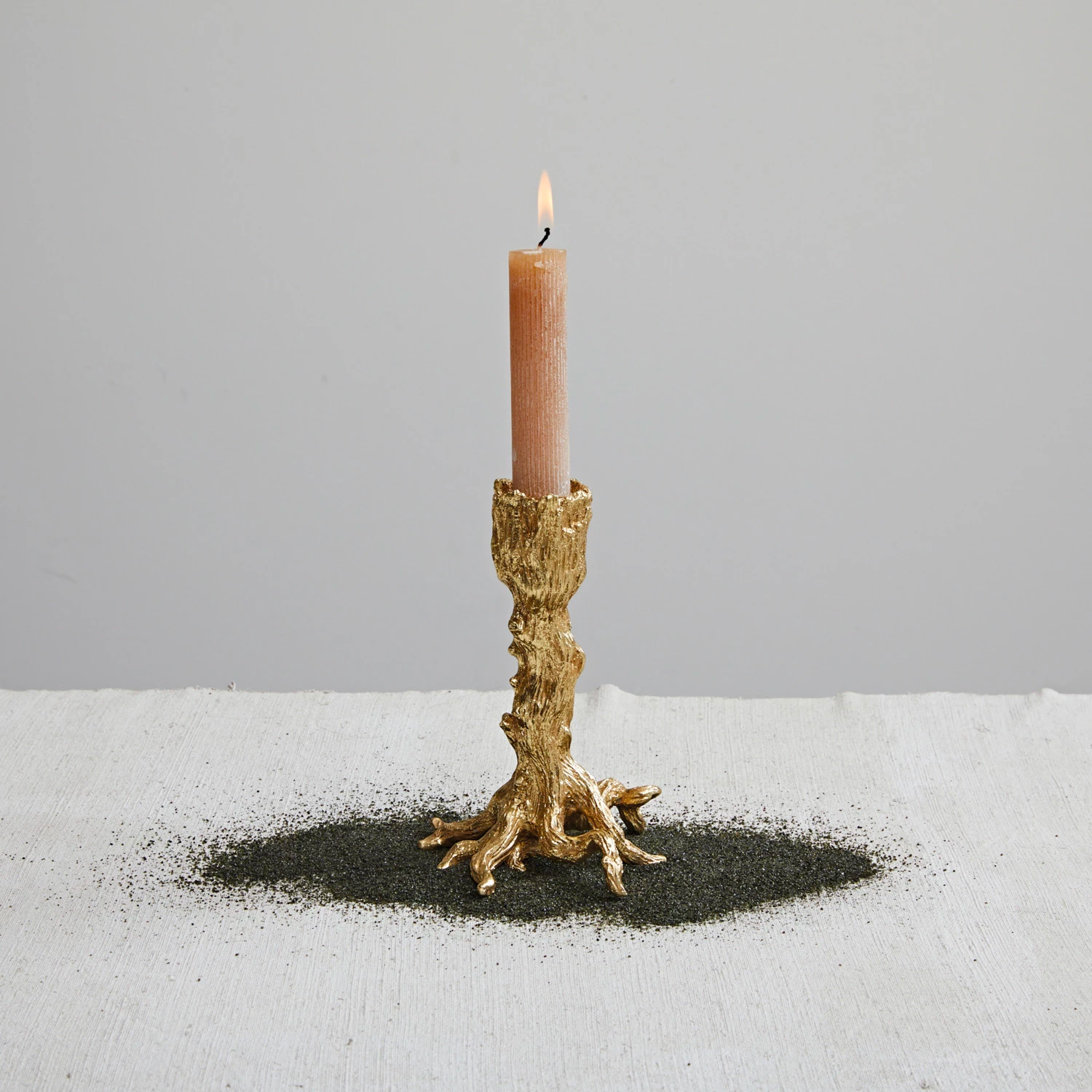 Candle in a decorative gold holder on a light gray background