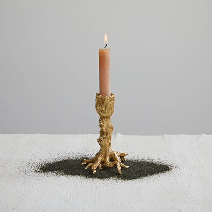 Candle in a decorative gold holder on a light gray background