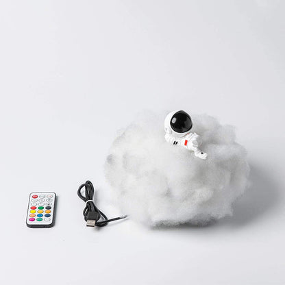 Toy robot on a cloud with a remote control and USB cable on a white background