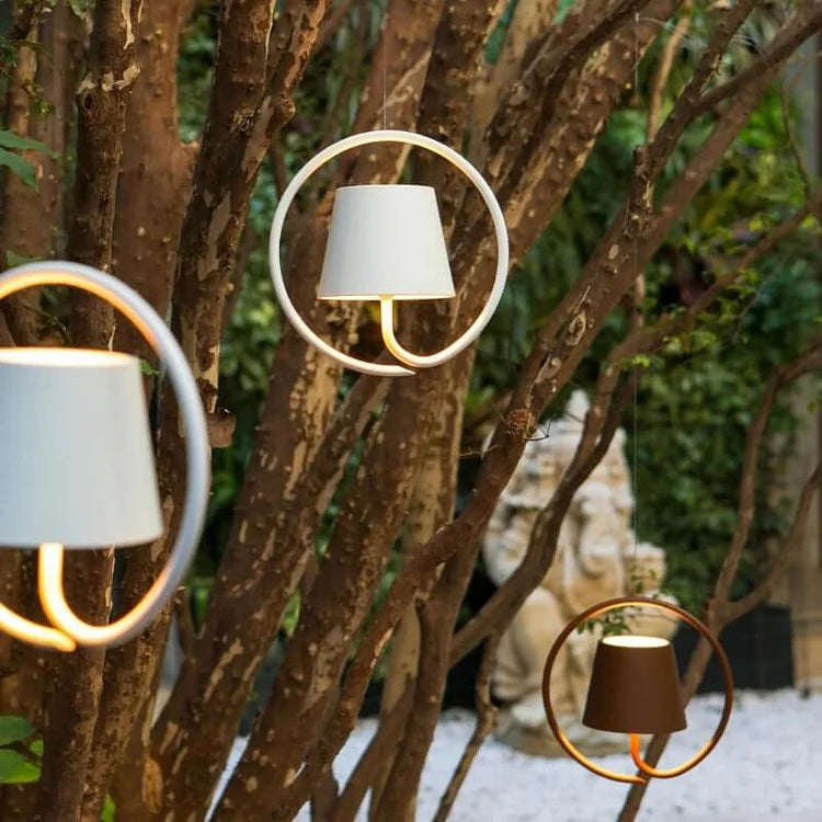 Decorative outdoor lamps with circular designs on a tree branch