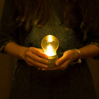 Person holding a light bulb in a dark setting