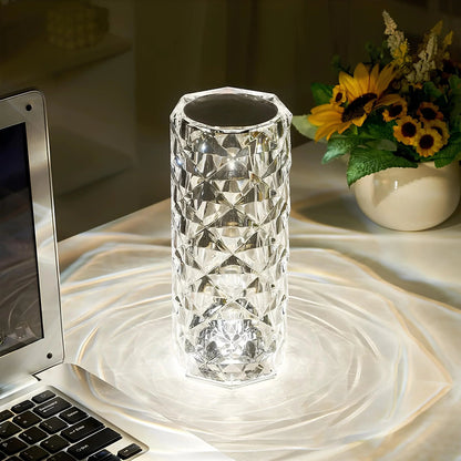 Crystal vase on a marble surface with a laptop and sunflower arrangement in the background