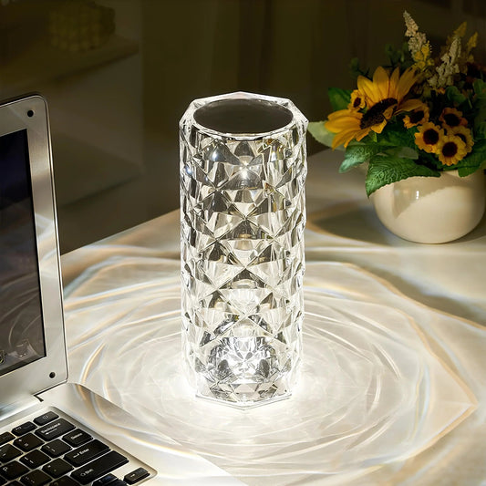 Crystal vase on a marble surface with a laptop and sunflower arrangement in the background