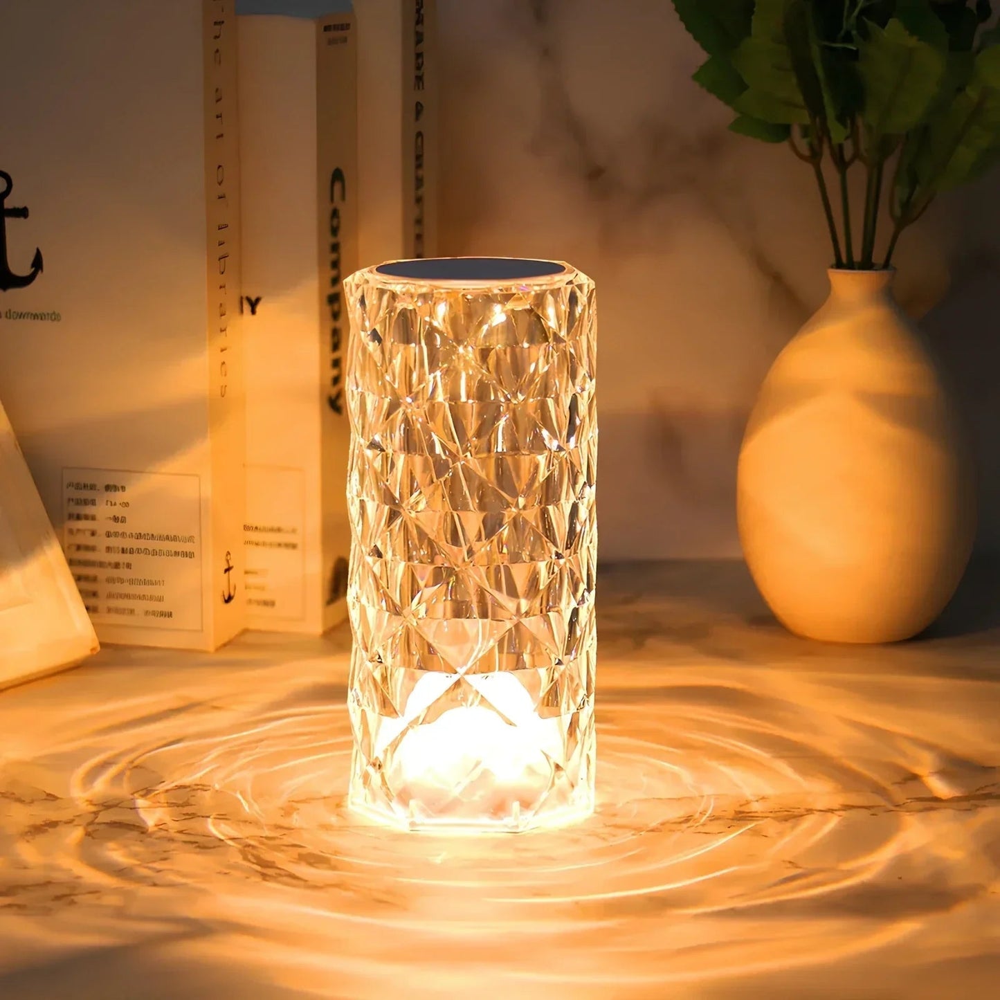 Decorative glass lamp with water effect on a table with books and a vase in the background