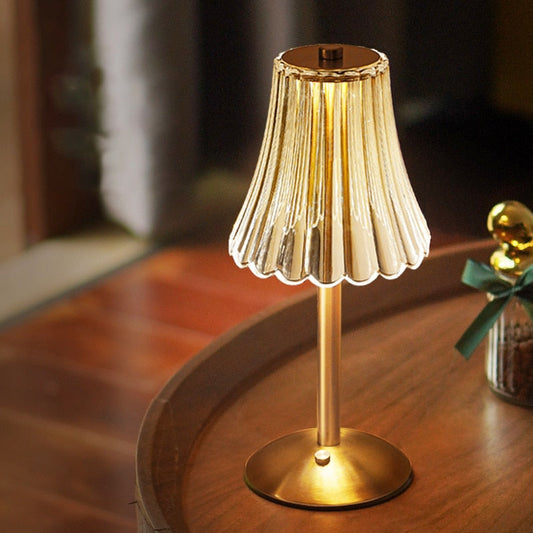 Gold table lamp with pleated shade on a wooden surface
