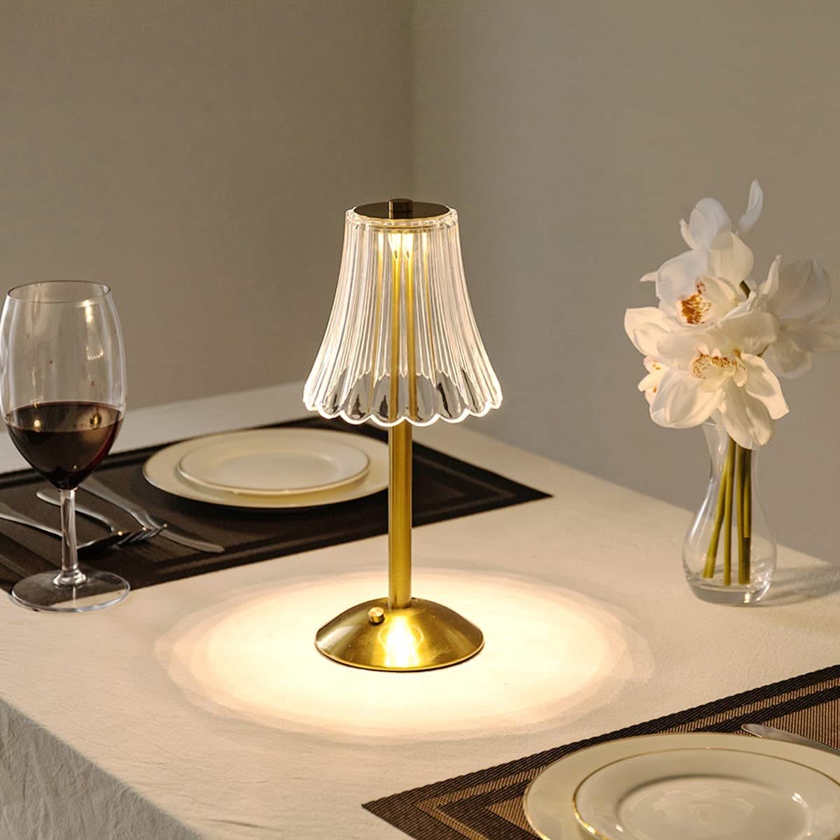 Gold table lamp on a dining table with wine glass and plates