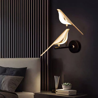 Modern wall lamp with bird design on a dark wall next to a sofa.